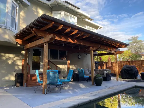 Covered patio with heavy cedar beams beside a pool