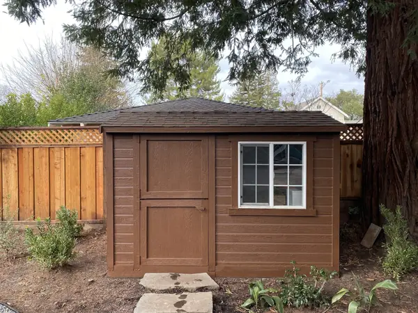 Brown wooden garden shed with stepping stones