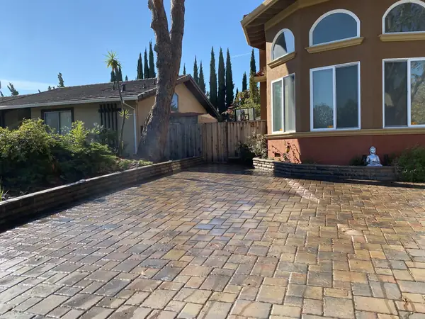 Multicolor paver driveway beside a stucco home