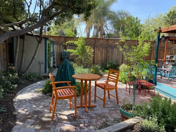 Garden patio with a circle of red pavers, planting and orange chairs
