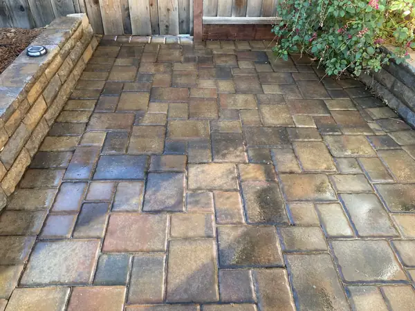 Warm-toned paver patio edged by a stone seat wall