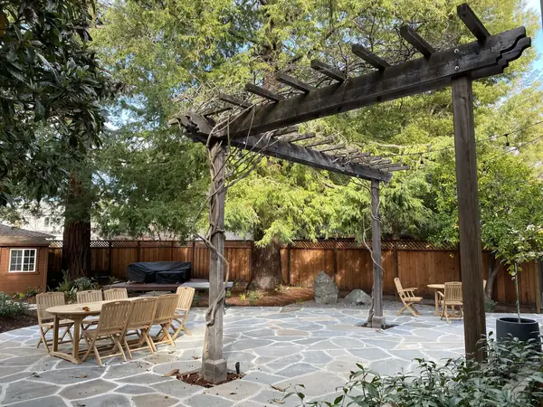 Flagstone patio with dining tables under a wooden pergola
