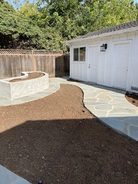 Curved concrete seat wall planter beside a flagstone path